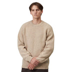 A man wearing a beige textured knit crewneck sweater, standing against a plain white background.