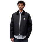 A man wearing a navy Carhartt jacket with a dark brown corduroy collar, a zippered chest pocket, and a visible Carhartt logo patch on the left chest.