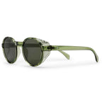 Oversized round sunglasses with a translucent olive green frame, dark lenses, and a silver-toned decorative metal accent on the front, shown on a white background.