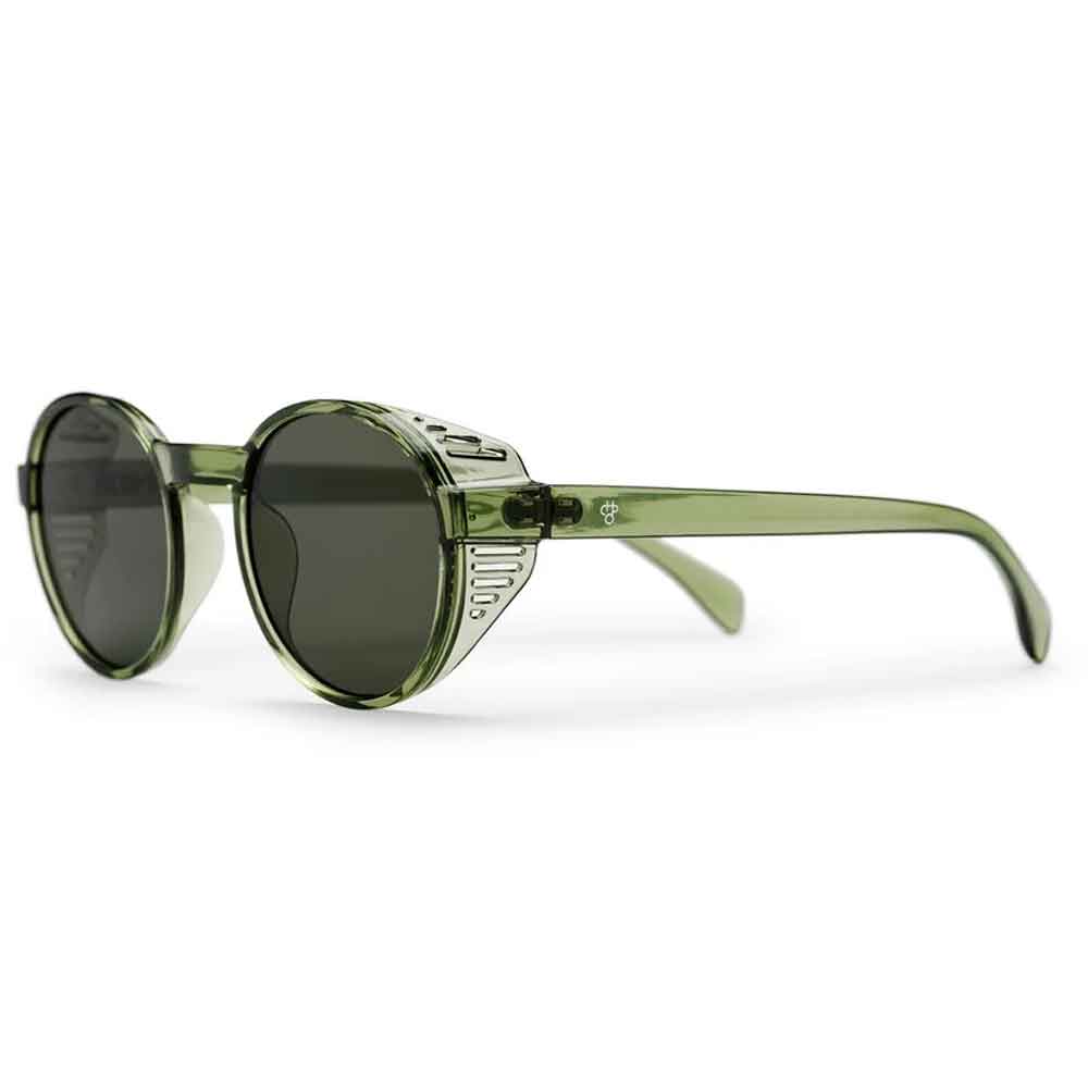 Oversized round sunglasses with a translucent olive green frame, dark lenses, and a silver-toned decorative metal accent on the front, shown on a white background.