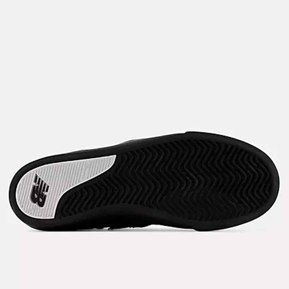 The black outsole of a New Balance sneaker, showing the textured tread pattern and the white New Balance 'NB' logo on the heel, set against a light gray background.