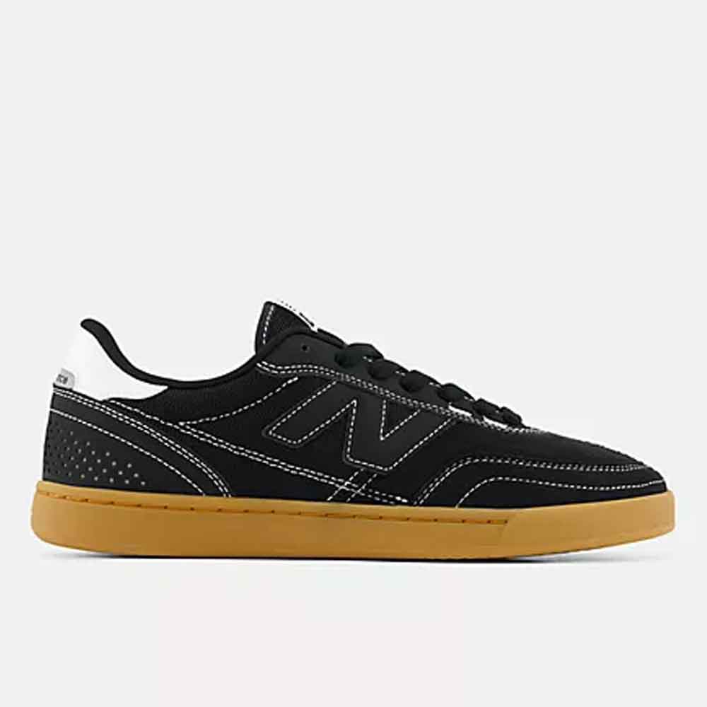 A black New Balance sneaker with white contrast stitching, a white heel tab, and a classic gum brown sole, shown in a side profile on a light gray background.