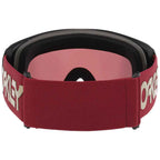 Oakley goggles with a burgundy elastic strap featuring a cream Oakley logo, a pink mirrored lens, and black foam padding.