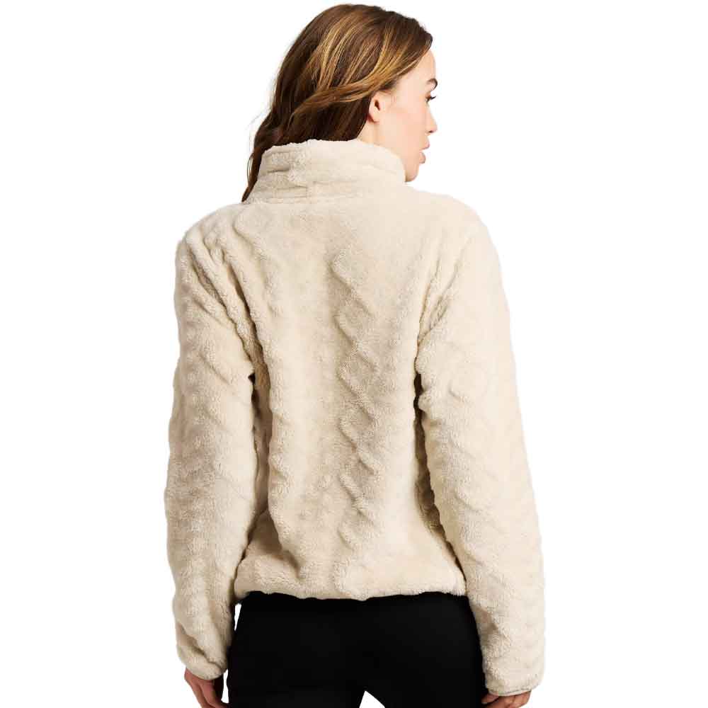 A woman shown from the back wearing a cream-colored, textured faux-fur jacket with a high mock neck and cable-knit pattern on the back, paired with black pants against a white background.