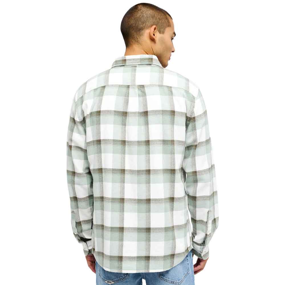 A man viewed from the back wearing a long-sleeve plaid button-up shirt in white, sage green, and brown, paired with blue jeans against a plain white background.