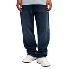 A person wearing dark blue straight-leg jeans with white sneakers, shown from the waist down on a plain white background.