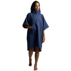 A woman wearing a navy blue hooded poncho-style towel or beach cover-up, standing against a plain white background.