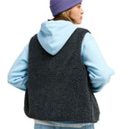 A woman shown from the back wearing a dark charcoal sherpa fleece vest over a light blue hoodie, with a purple beanie, against a plain white background.