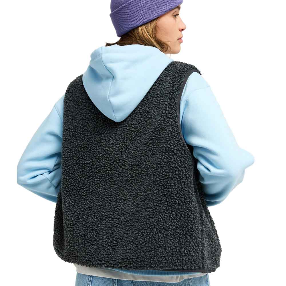 A woman shown from the back wearing a dark charcoal sherpa fleece vest over a light blue hoodie, with a purple beanie, against a plain white background.