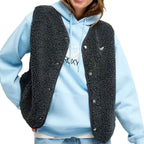 A person wearing a light blue hoodie with a black sherpa fleece vest layered over it, shown from the neck down against a plain white background.