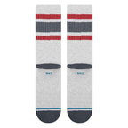 A pair of Stance crew socks in light heather gray, featuring red and navy blue striped bands near the cuff, a dark gray heel, and a navy blue toe with a thin light blue stripe.