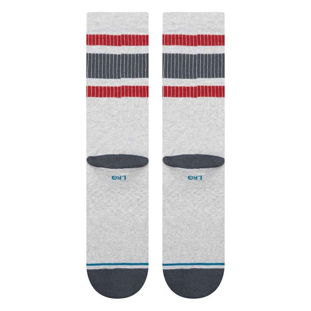 A pair of Stance crew socks in light heather gray, featuring red and navy blue striped bands near the cuff, a dark gray heel, and a navy blue toe with a thin light blue stripe.