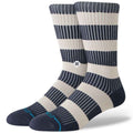A pair of crew socks with navy blue and cream horizontal stripes, featuring thin vertical pinstripes, a small circular logo on the calf, and a light blue brand accent on the toes.