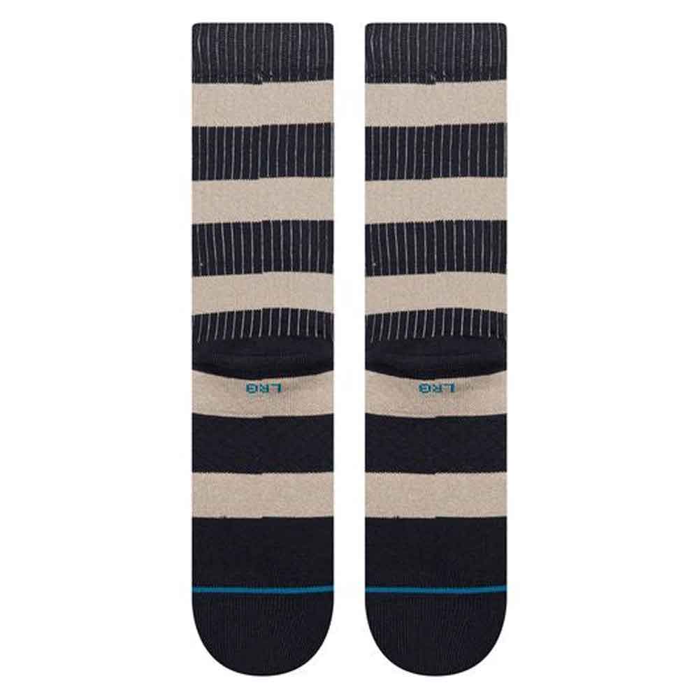 A pair of Stance crew socks with horizontal stripes in navy blue, beige, and thin white pinstripes, featuring a light blue Stance logo on the side.