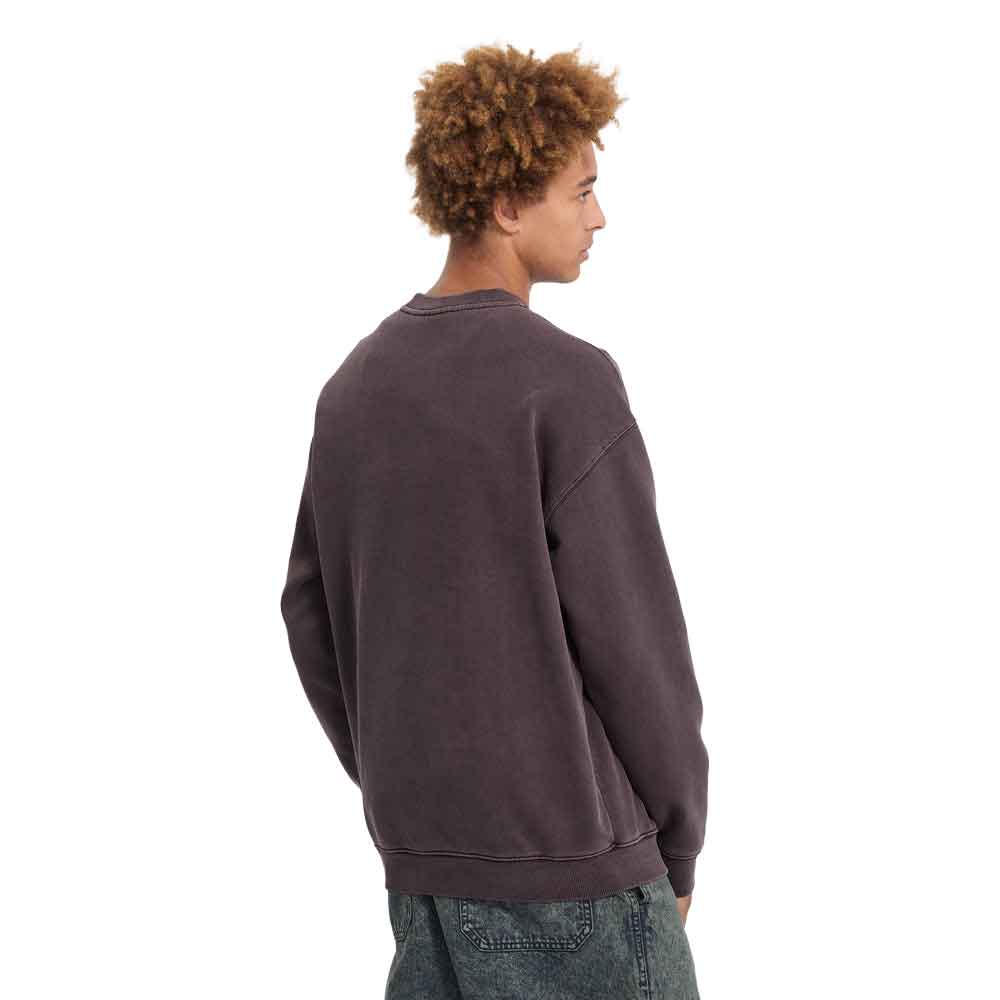 A man with curly brown hair is shown from the back wearing a washed dark plum-brown crewneck sweatshirt and blue jeans against a plain white background.