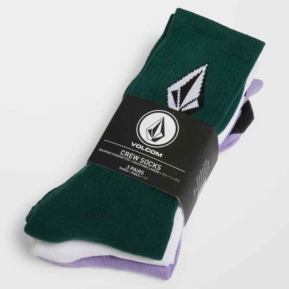 Volcom crew socks in a 3-pack, featuring a dark forest green pair with a white and black arrowhead logo, a white pair, and a light purple pair, all wrapped in a black paper band.