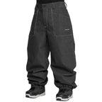 Dark gray Volcom snow pants with contrast white stitching, shown on a model from the waist down wearing black and white sneakers against a white background.